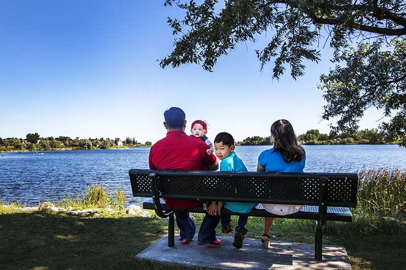A family sitting on a bench near the lake