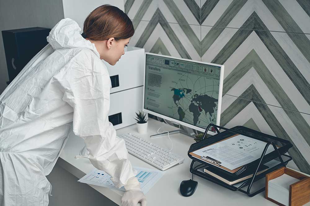 Back view of a beautiful young woman in a safety suit using a computer in a hospital connected to high speed fibre internet