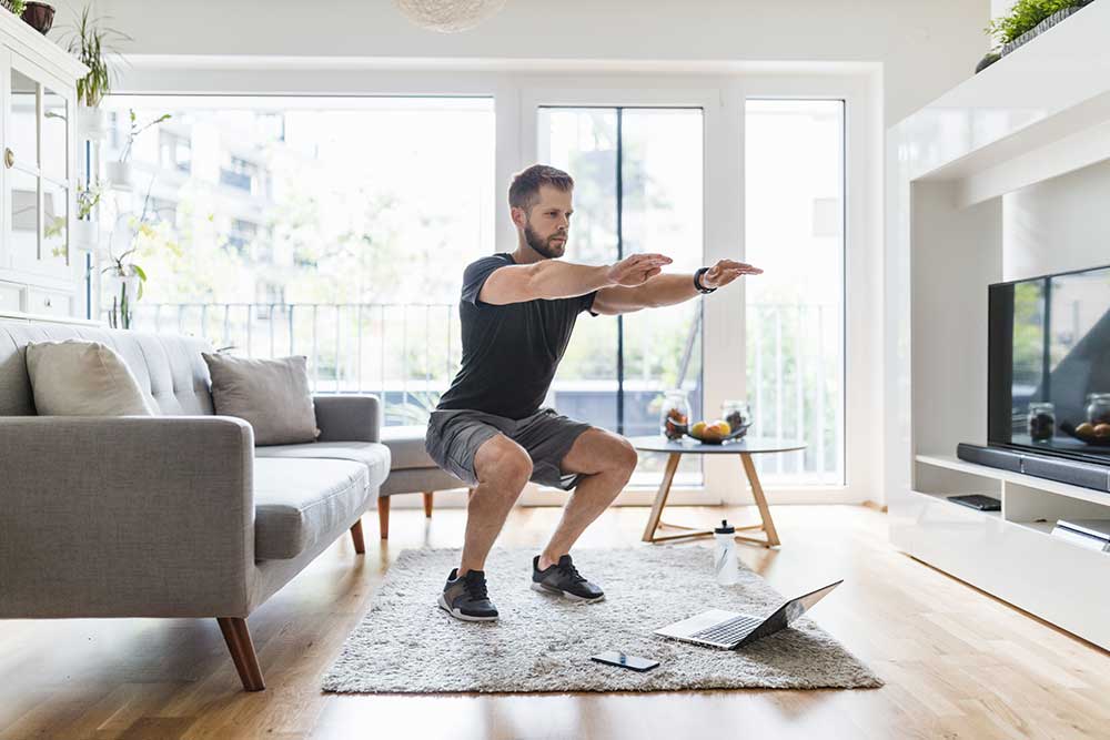 Young man working out at home in the living room.